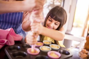 Little girl and her mom making cupcakes together